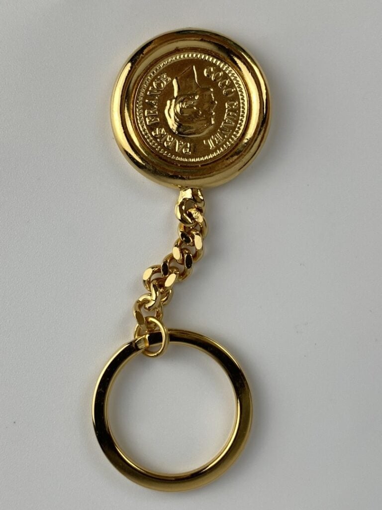 CHANEL - Porte-clé en métal doré orné du profil de Coco Chanel au recto, et du…