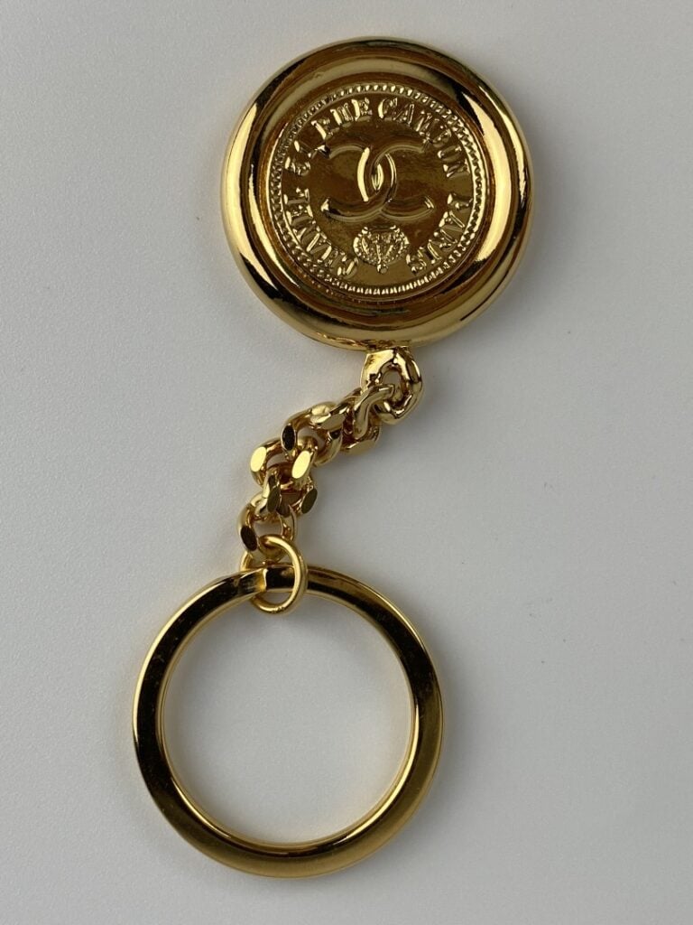 CHANEL - Porte-clé en métal doré orné du profil de Coco Chanel au recto, et du…