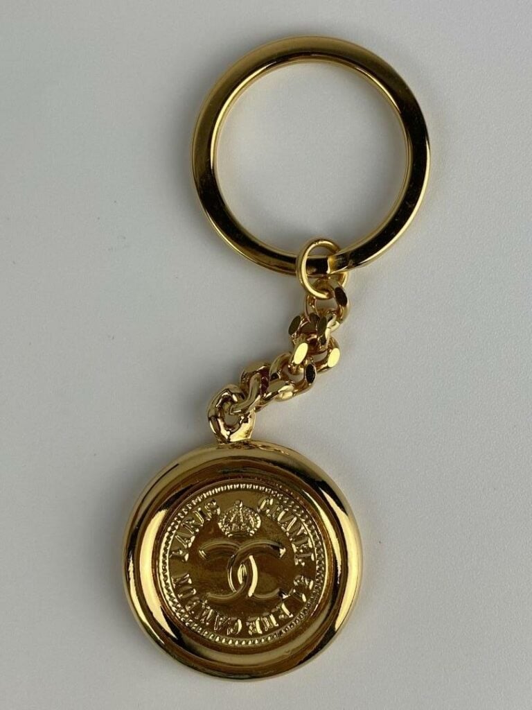 CHANEL - Porte-clé en métal doré orné du profil de Coco Chanel au recto, et du…