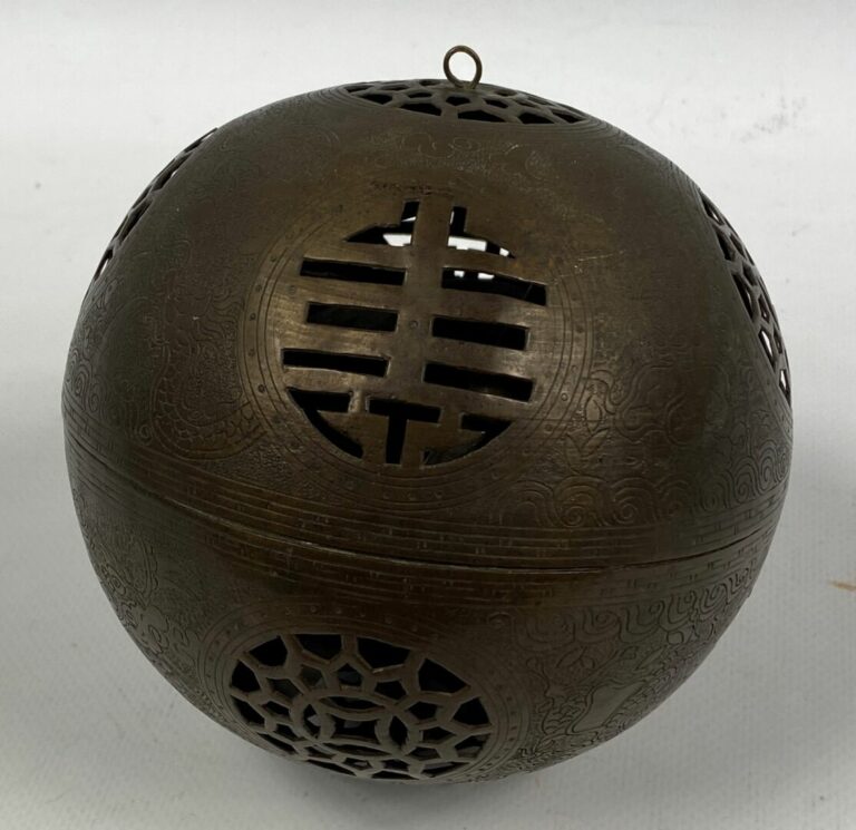 CHINE, XXe siècle - Sphère ajourée en bronze à patine brune, ouvrant en son cen…