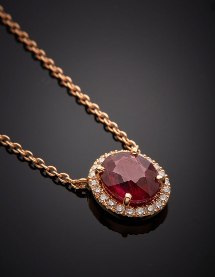 COLLIER en or rose (750‰) retenant un motif ovale, serti d'un rubis pesant 3,29…