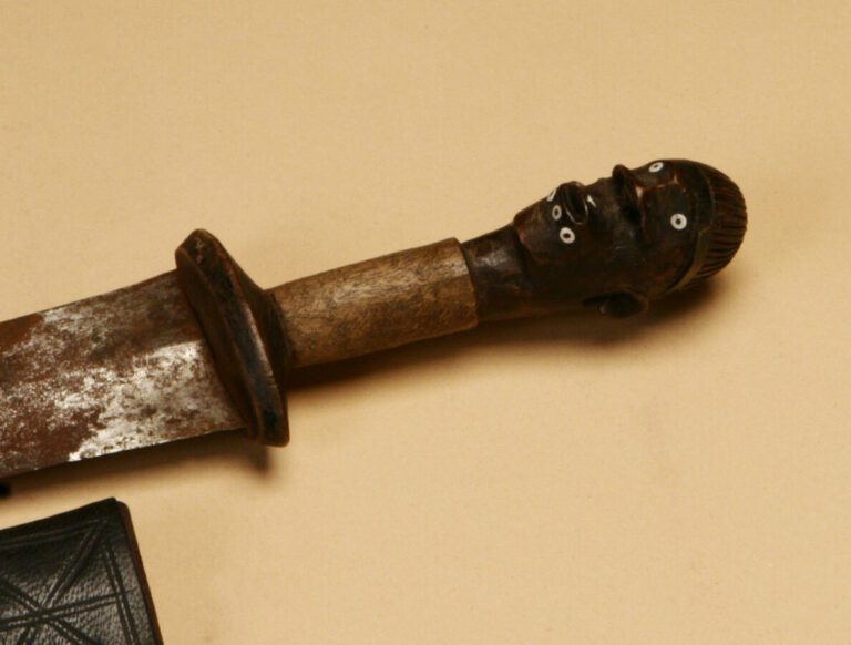 Couteau poignée en bois sculptée d'une tête humaine aux yeux et à la lèvre infé…