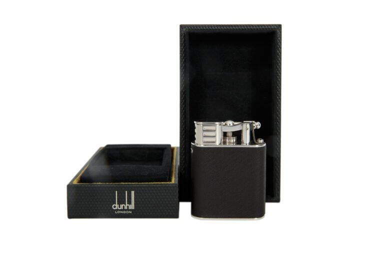 DUNHILL. - Briquet en métal argenté garni à l'imitation du cuir, dans son étui…