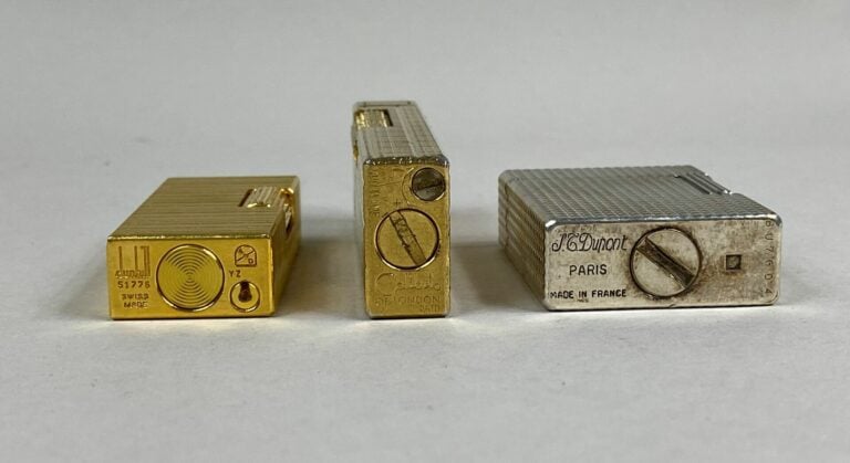 DUPONT, DUNHILL, COLIBRI - Lot de trois briquets en métal argenté ou doré à mot…