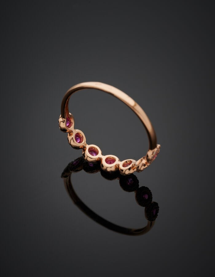 Fine BAGUE en or rose (750‰) serti de sept rubis ronds, chacun entouré de petit…
