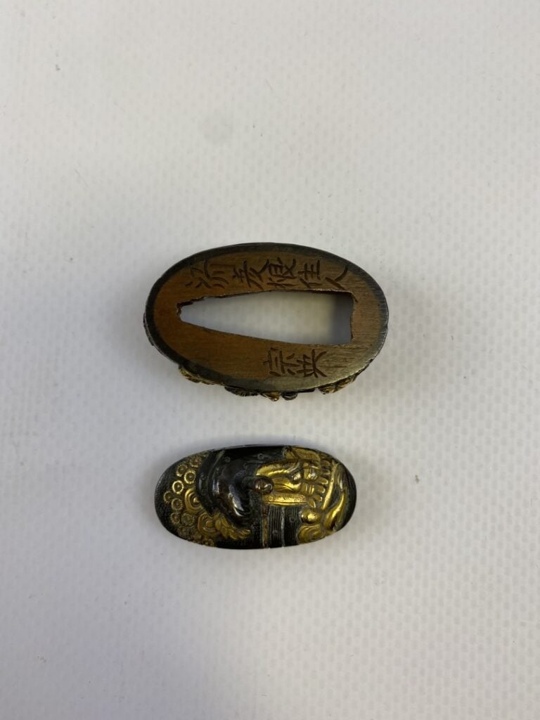 FUCHI KASHIRA EN FER REHAUSSE D'OR - Japon - Au décor de personnages dont un pê…