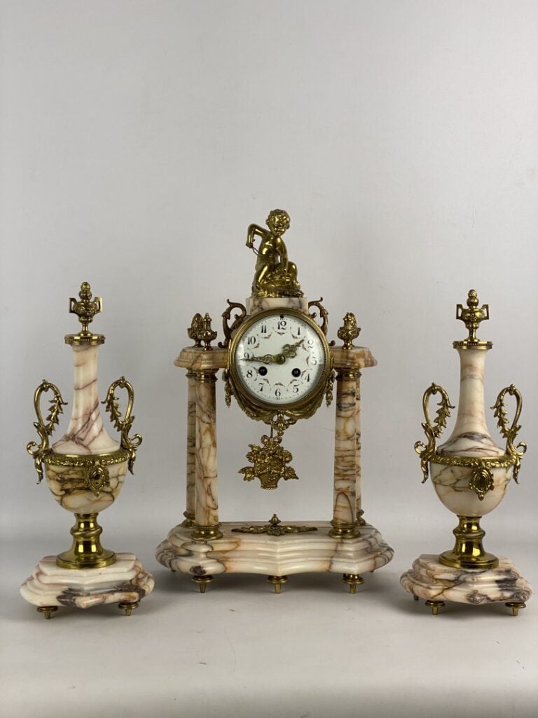 Garniture de cheminée comprenant : une pendule portique surmontée d'un putto et…