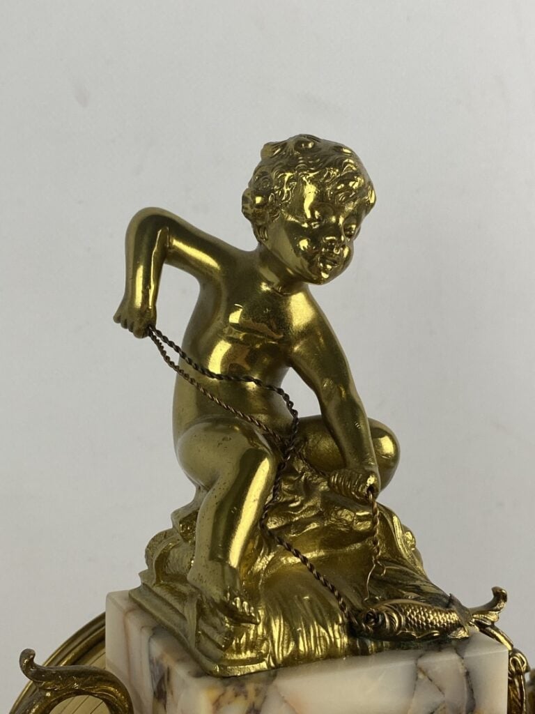 Garniture de cheminée comprenant : une pendule portique surmontée d'un putto et…