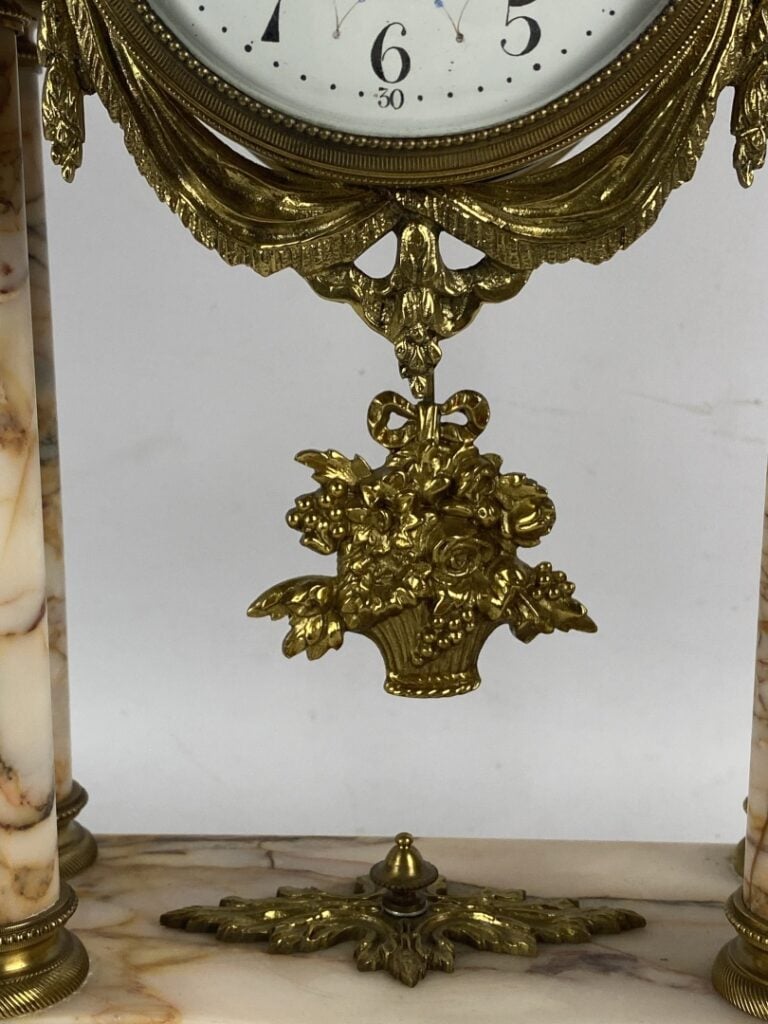 Garniture de cheminée comprenant : une pendule portique surmontée d'un putto et…