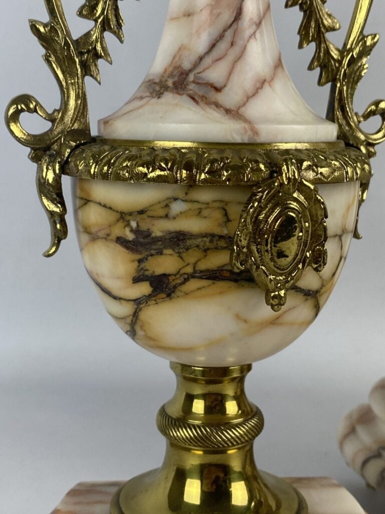 Garniture de cheminée comprenant : une pendule portique surmontée d'un putto et…