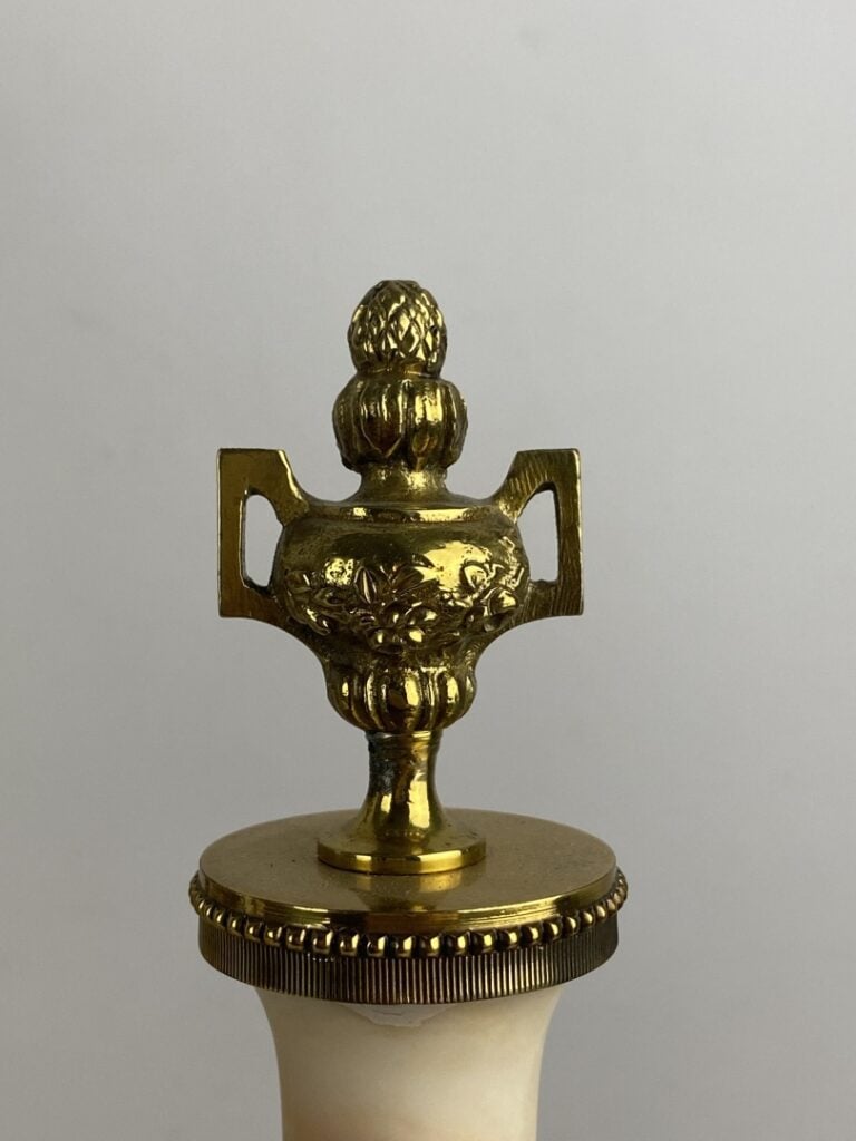 Garniture de cheminée comprenant : une pendule portique surmontée d'un putto et…