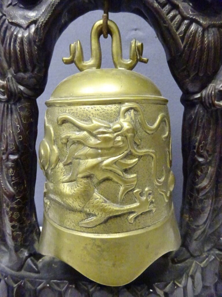 GRANDE CLOCHE DE TEMPLE AVEC SON SUPPORT EN BOIS A L'EFFIGIE DE DEUX FEMMES - V…