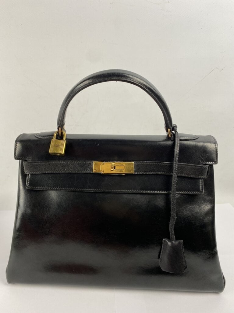 HERMÈS - Sac «Kelly» en box noir, attributs dorés, clefs cadenas, clochette ajo…