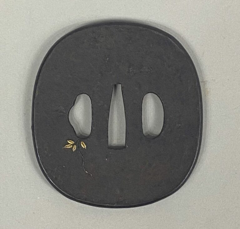 JAPON - Tsuba en fer à décor incrusté doré de branchages fleuris et sauterelle.…
