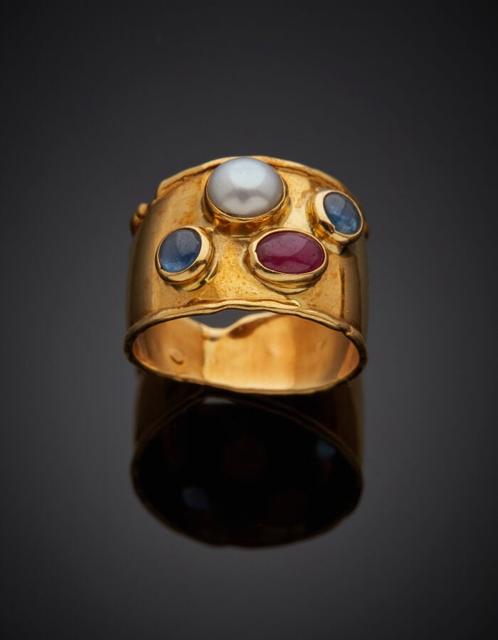 Large BAGUE bordée en or jaune (750‰) serti de deux saphirs, un rubis cabochons…