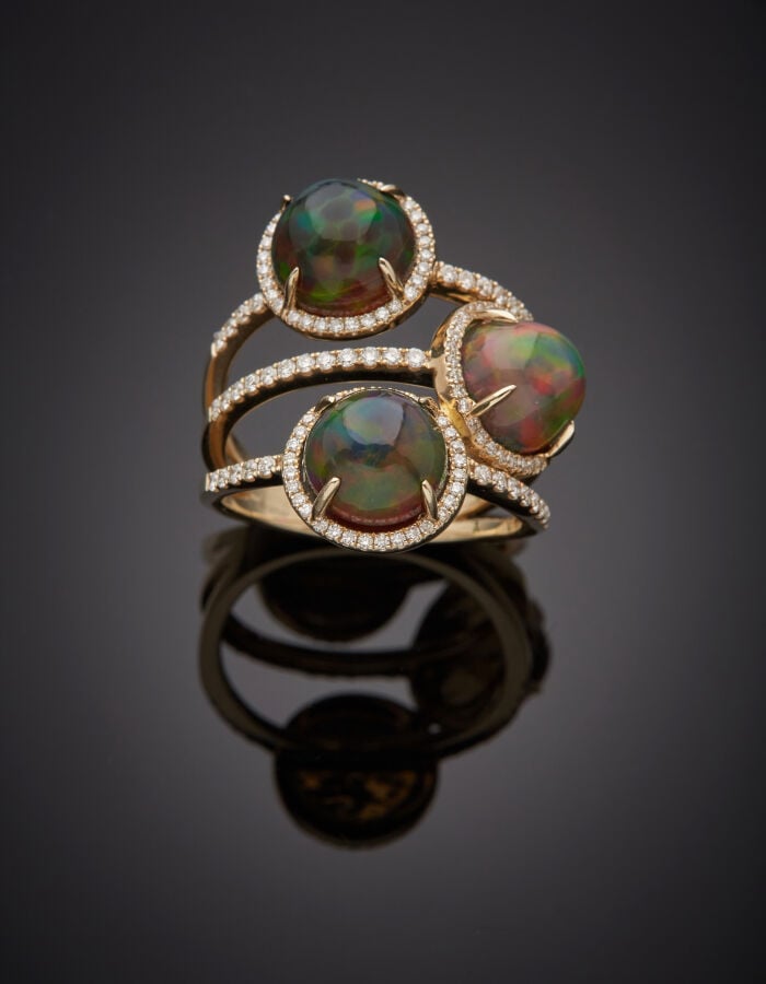Large BAGUE en or jaune (750‰) ajouré, orné de trois opales noires cabochons de…