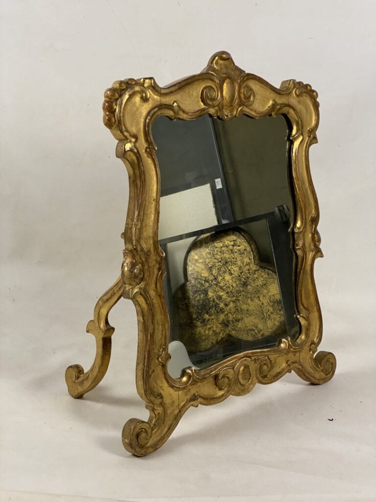 Miroir à poser en bois et stuc doré à décor d'enroulements et surmonté d'une co…