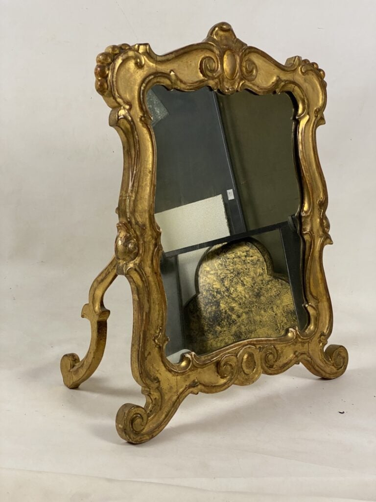 Miroir à poser en bois et stuc doré à décor d'enroulements et surmonté d'une co…