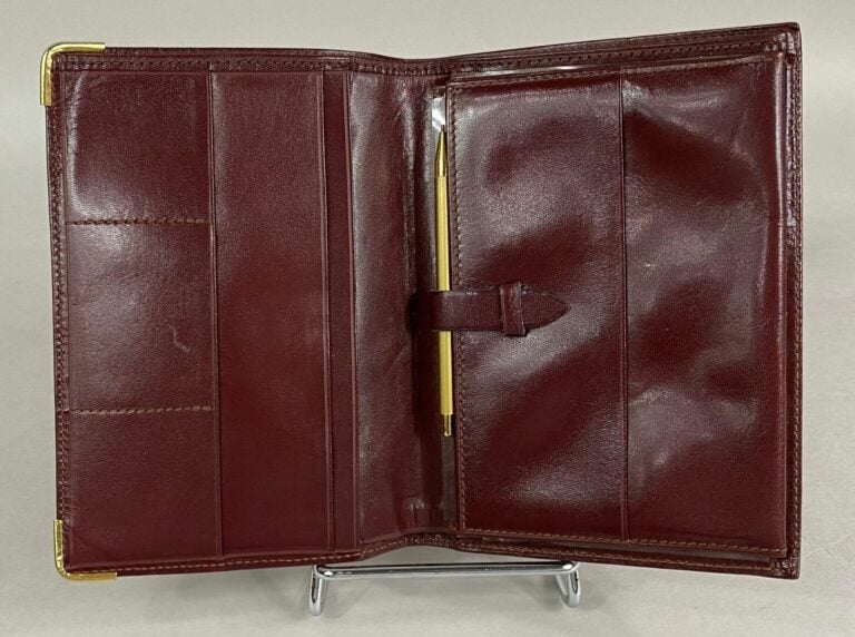 Must de CARTIER - Portefeuille à compartiments en cuir bordeaux - 15 x 10.5 cm…