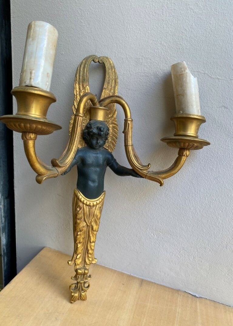 Paire d'appliques en bronze patiné et doré, figurant des jeunes hommes tenant d…
