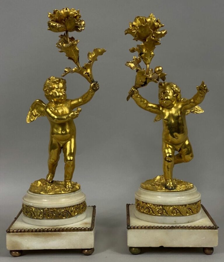 Paire de bougeoirs en bronze ciselé et doré figurant des putti ailés supportant…