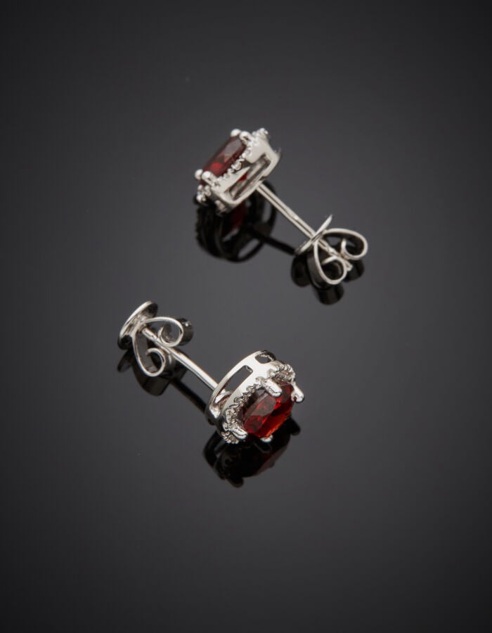 Paire de CLOUS d'OREILLES circulaires en or gris (750‰) serti d'un grenat pyrop…