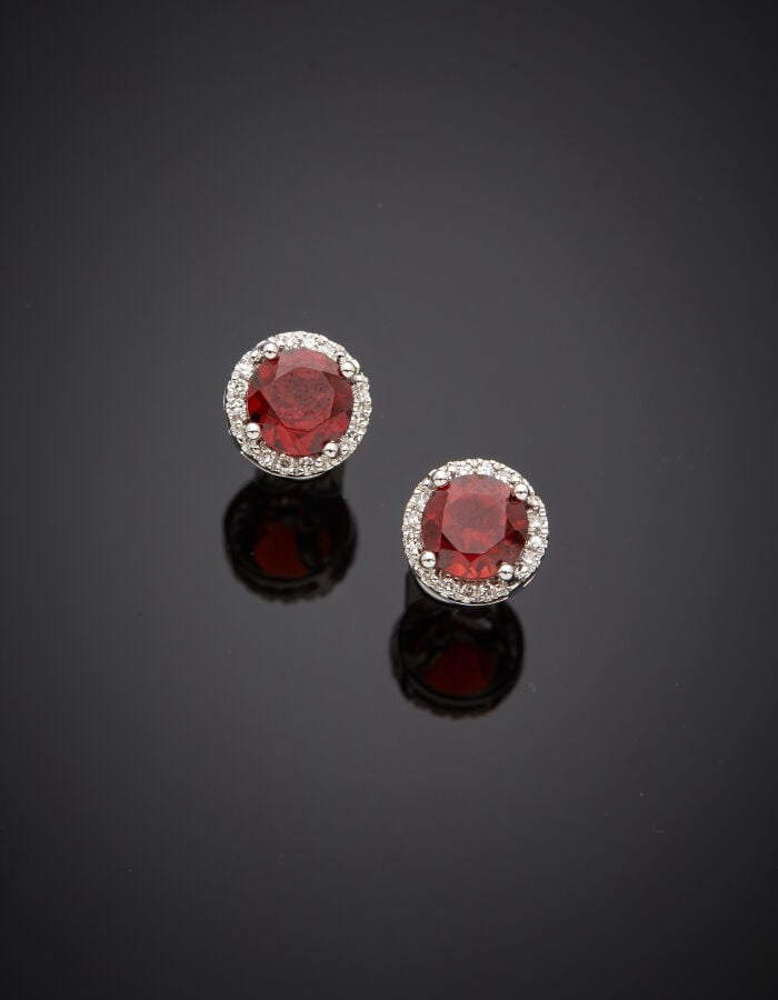 Paire de CLOUS d'OREILLES circulaires en or gris (750‰) serti d'un grenat pyrop…