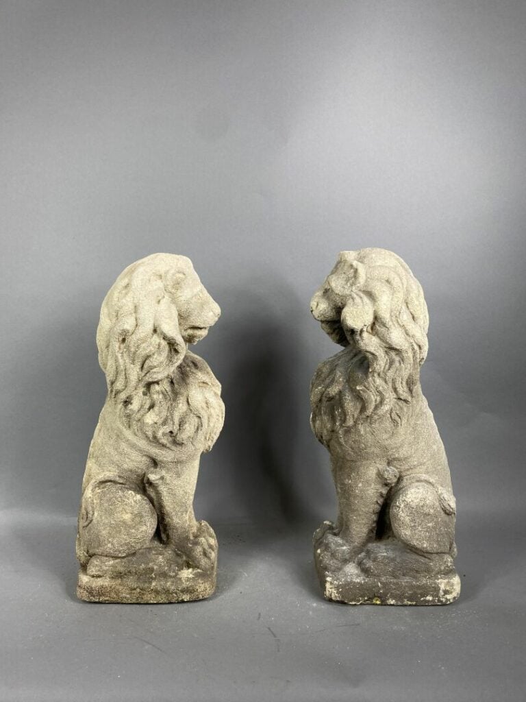 Paire d'ornements d'extérieur en pierre reconstituée figurant des lions assis -…