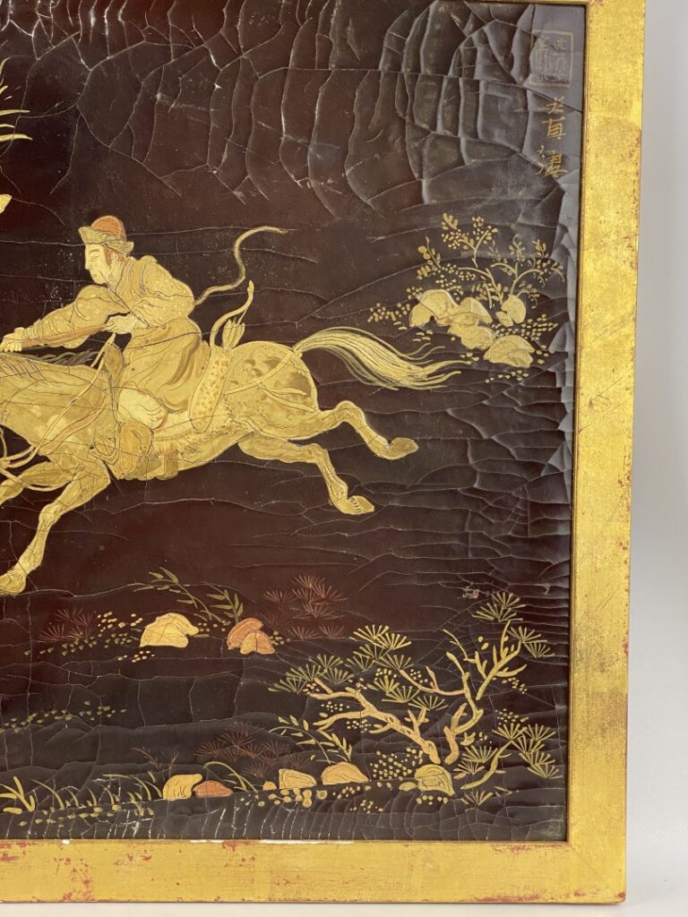 Panneau laqué noir et doré à décor de cavaliers et chevaux sauvages, dans le go…