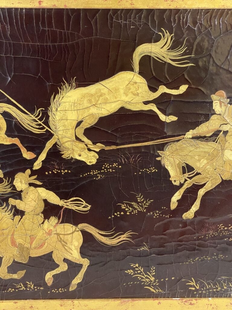 Panneau laqué noir et doré à décor de cavaliers et chevaux sauvages, dans le go…