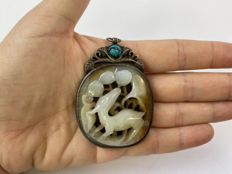 Pendentif en jade céladon et rouille, sculpté d'un daim parmi les pins - Chine,…