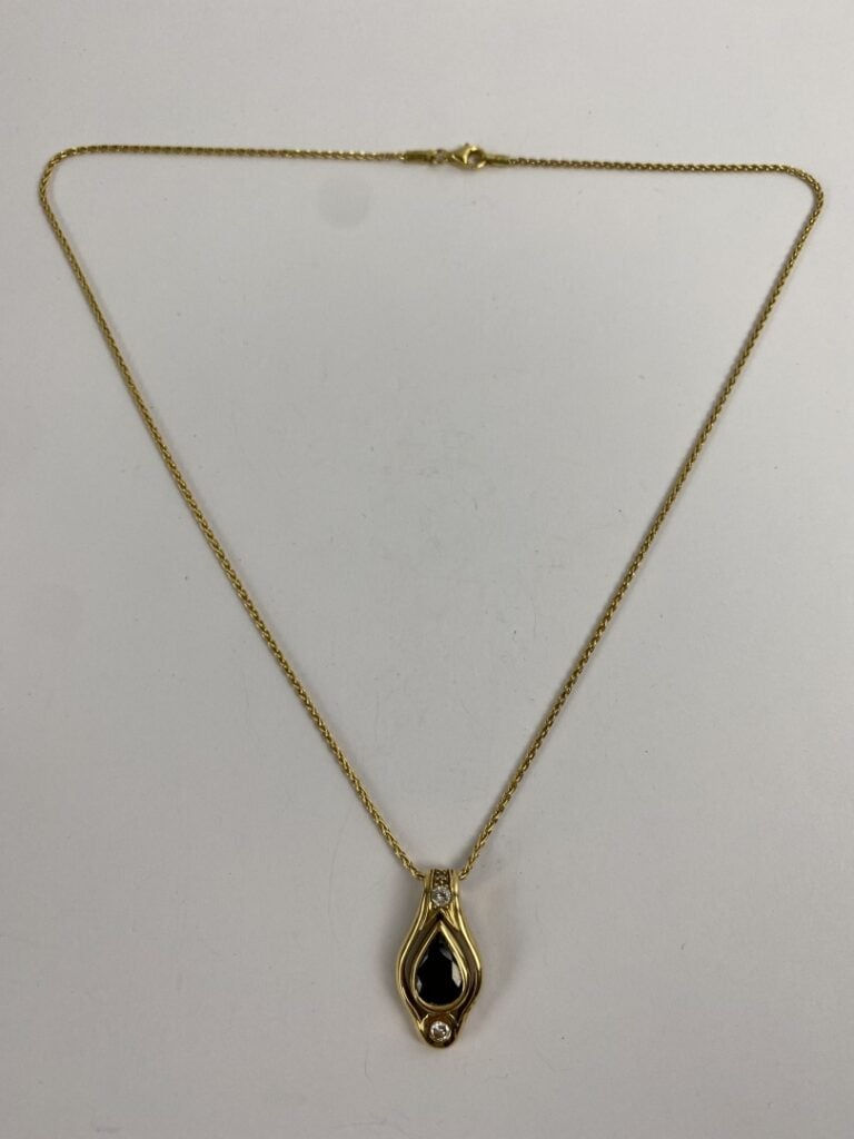 Pendentif en or jaune (750) ajouré de forme violonée centré d'un saphir de tail…