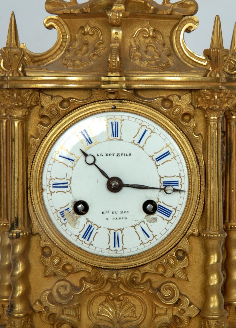 Pendule en bronze ciselé et doré, le sommet est pourvu d'un vase,montants en de…