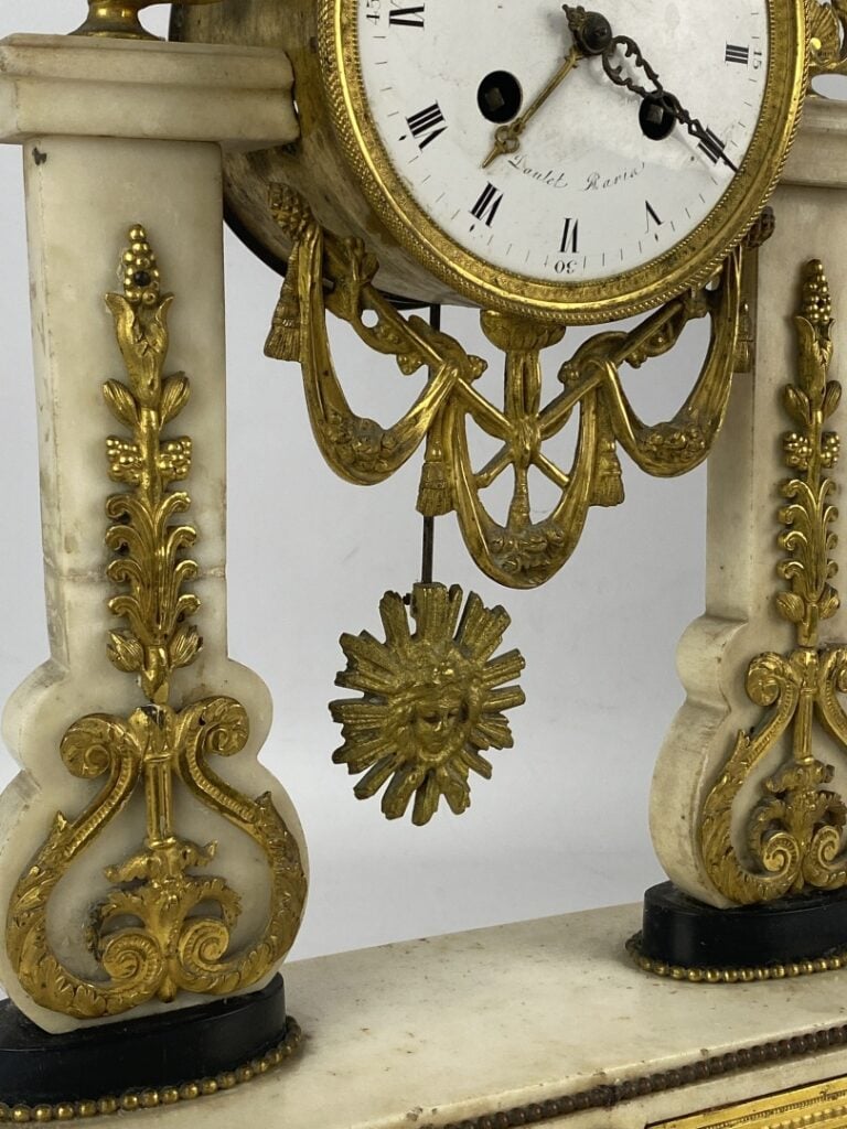 Pendule portique en marbre blanc et noir et bronze cisélé à décor de perles, fe…