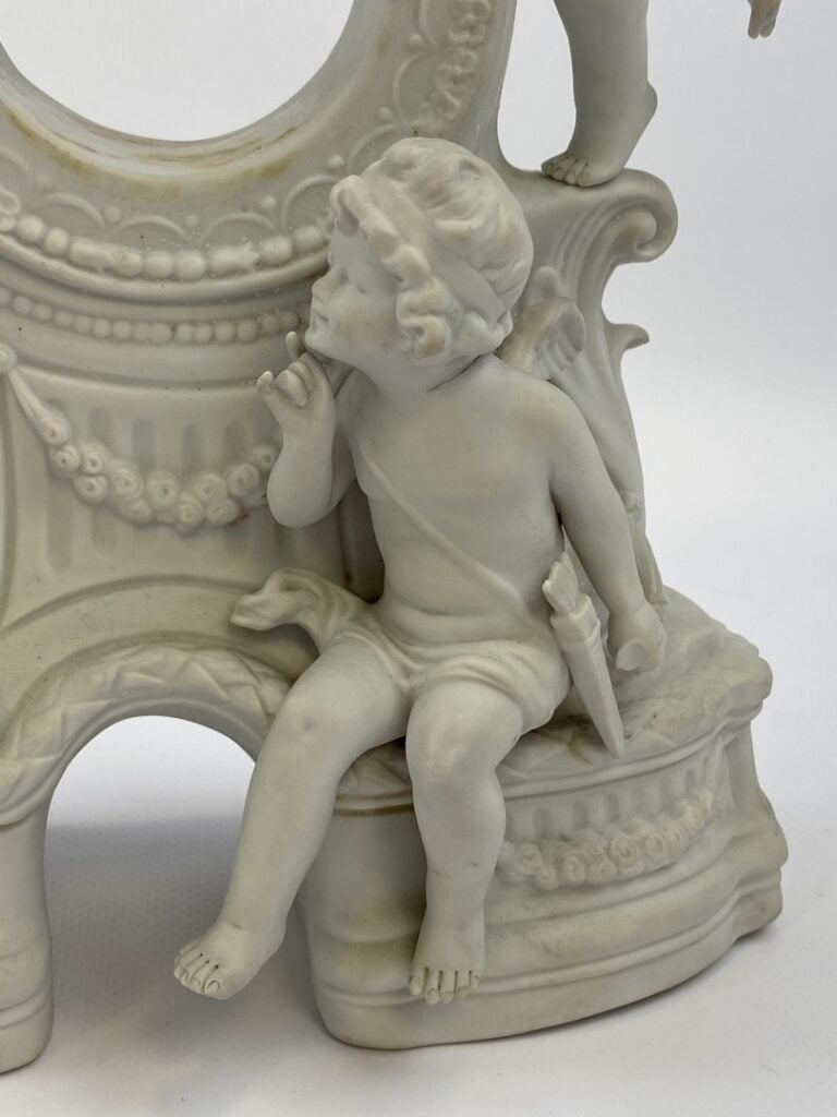 Porte montre en biscuit à décor d'angelots - (traces, manques) - 27 x 22 cm - R…