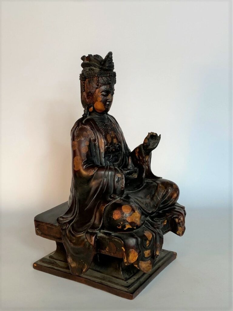 STATUE D'UNE DIVINITE EN BOIS LAQUE - XXe siècle - Assis sur un socle carré, el…