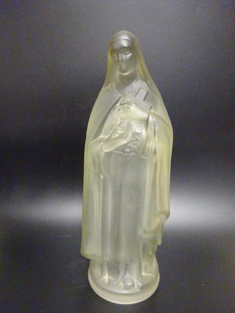 Statue en verre pressé moulé représentant une Vierge tenant une croix fleurie.…