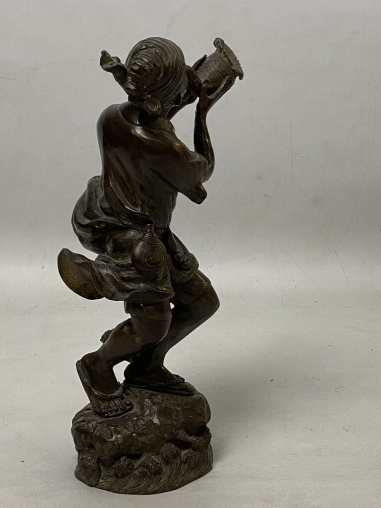 Sujet en bronze à patine brune figurant un homme debout soufflant dans une conq…