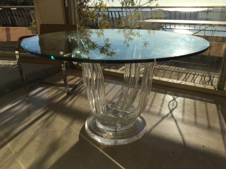 Table de salle à manger en résine, le plateau en verre reposant sur un piétemen…