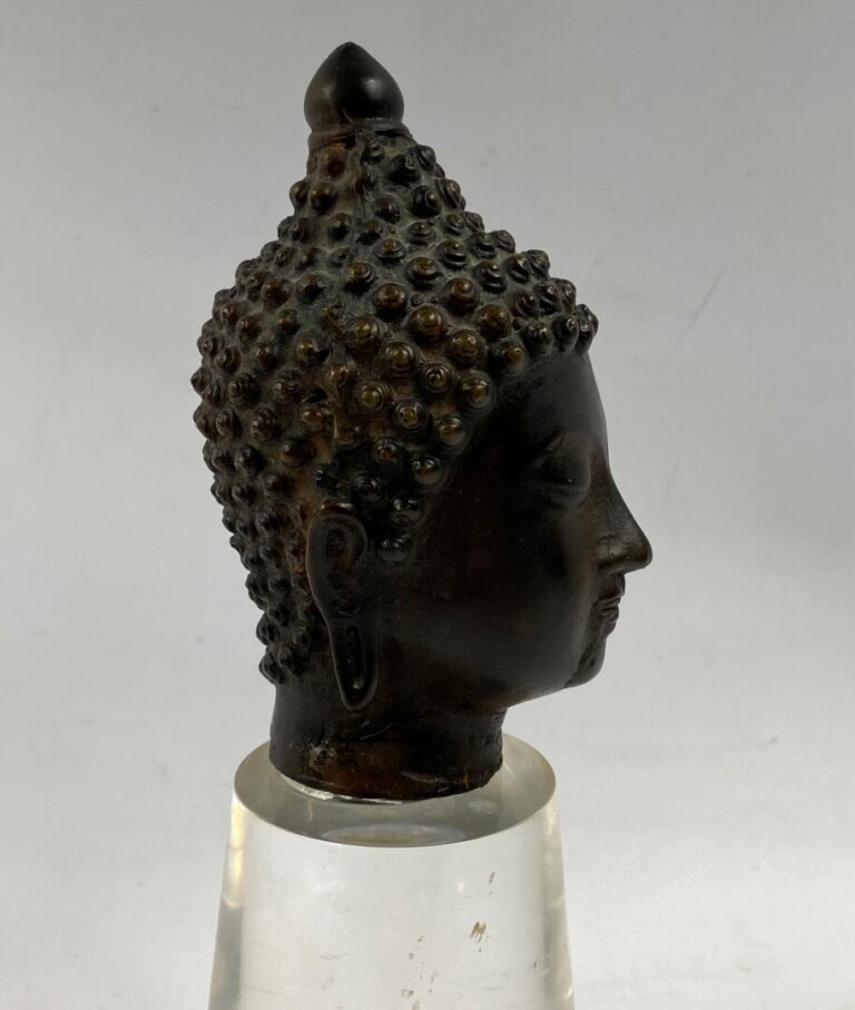 THAILANDE - Tête de bouddha en bronze. Le visage serein, il est représenté les…