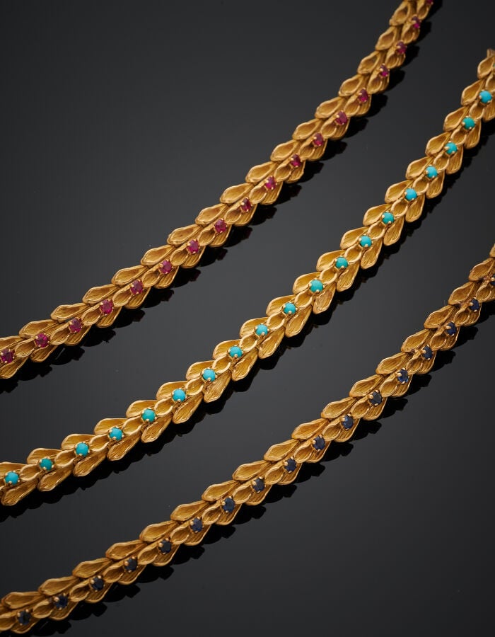 Trois BRACELETS articulés, en suite, en or jaune (750‰) ciselé et dépoli, à mot…