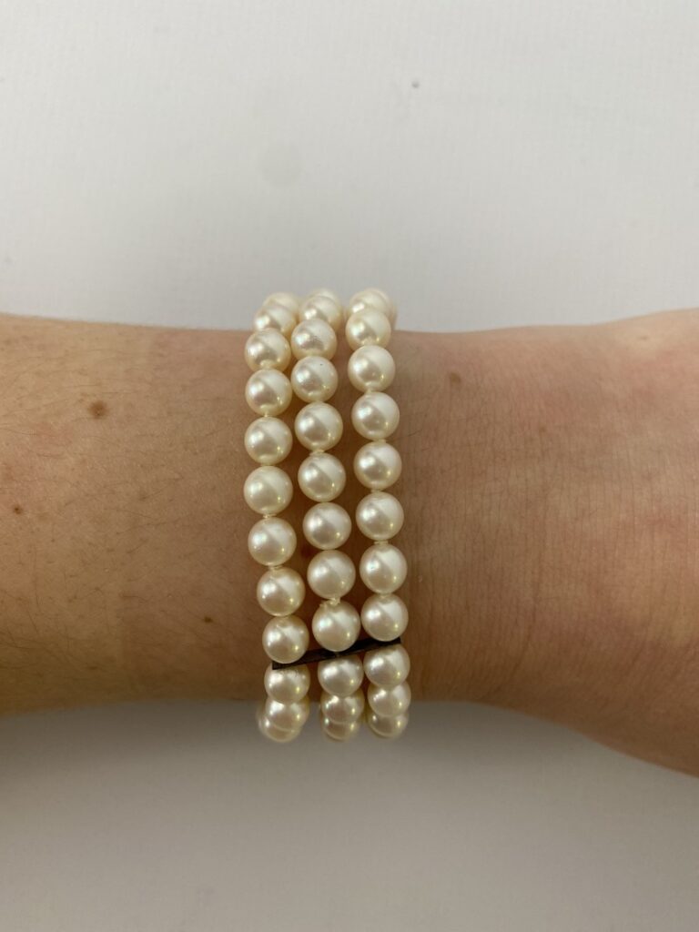 Un bracelet à trois rangs de perles, fermoir imitant l'or gris. - (un rang à re…