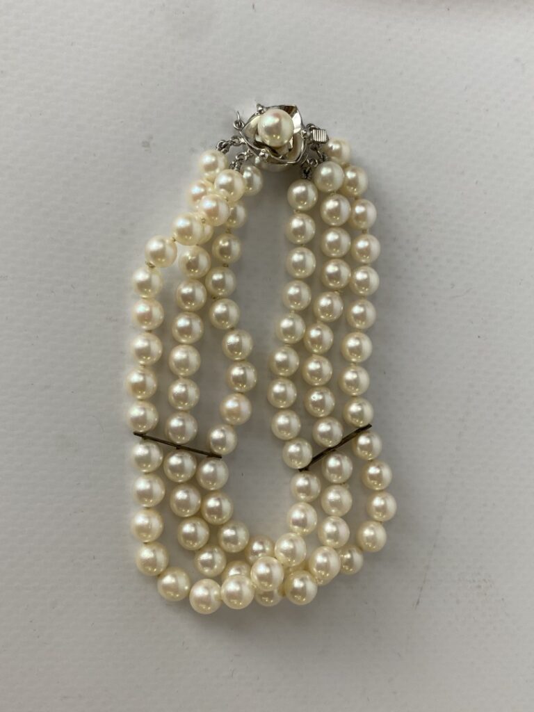 Un bracelet à trois rangs de perles, fermoir imitant l'or gris. - (un rang à re…