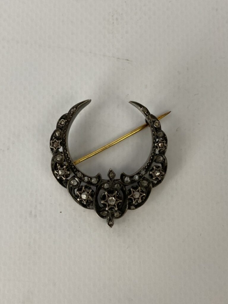 Une broche de forme demi-lune en argent partiellement doré, sertie de petits br…