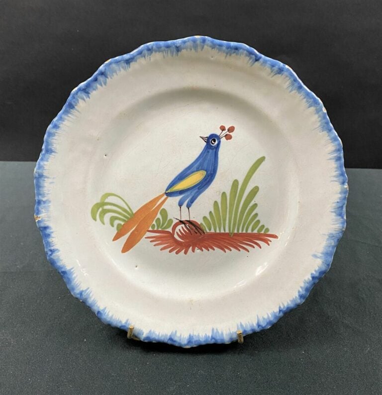 WALY - Assiette à bord contourné, décor polychrome d'un paon posé sur un tertre…