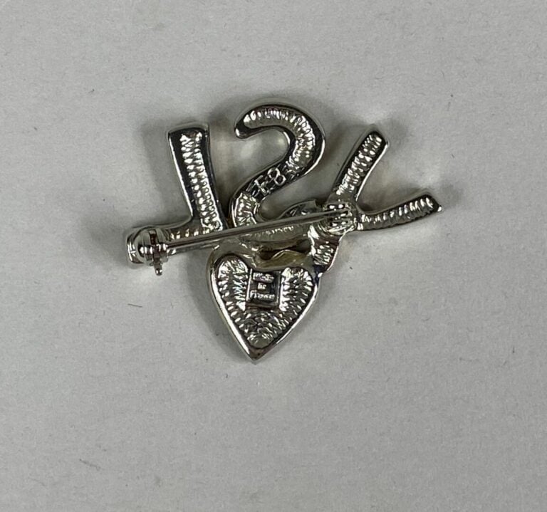 Yves SAINT LAURENT - Broche en métal argenté "YSL" ornée d'un coeur et pavée de…