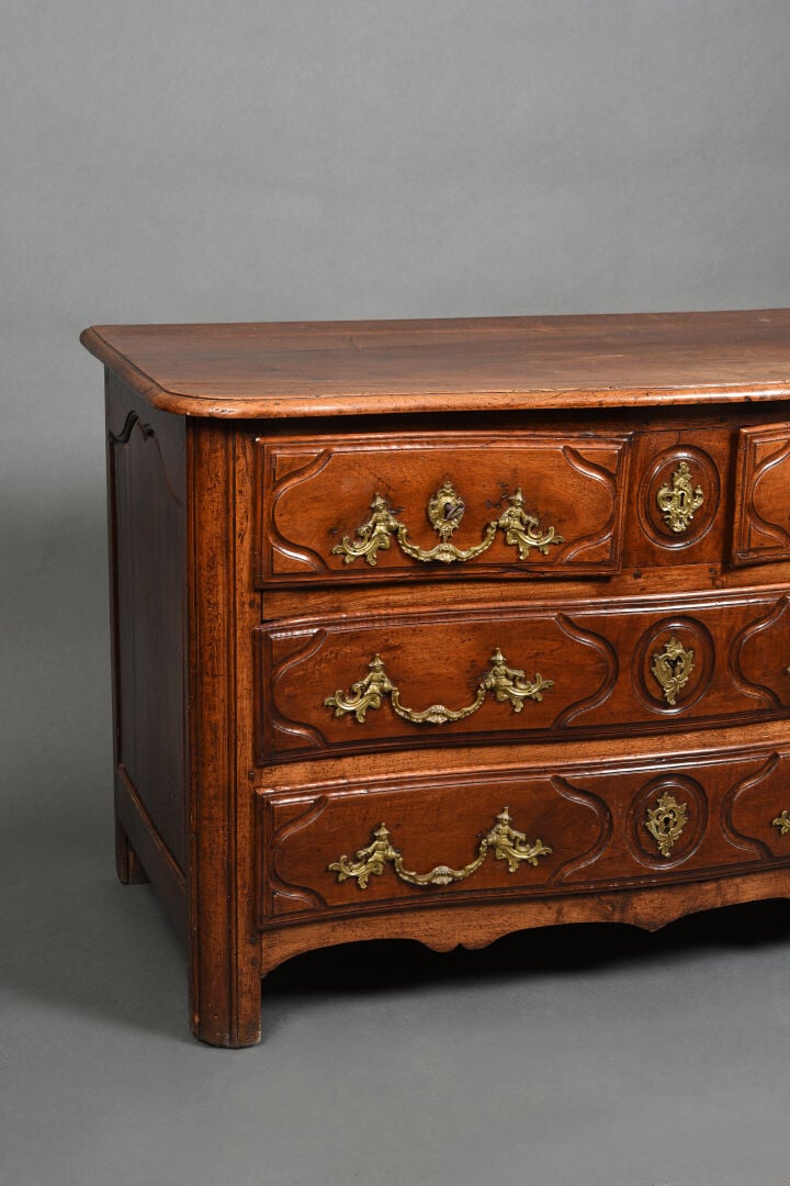Commode à façade cintrée en noyer mouluré ouvrant par quatre tiroirs sur trois…