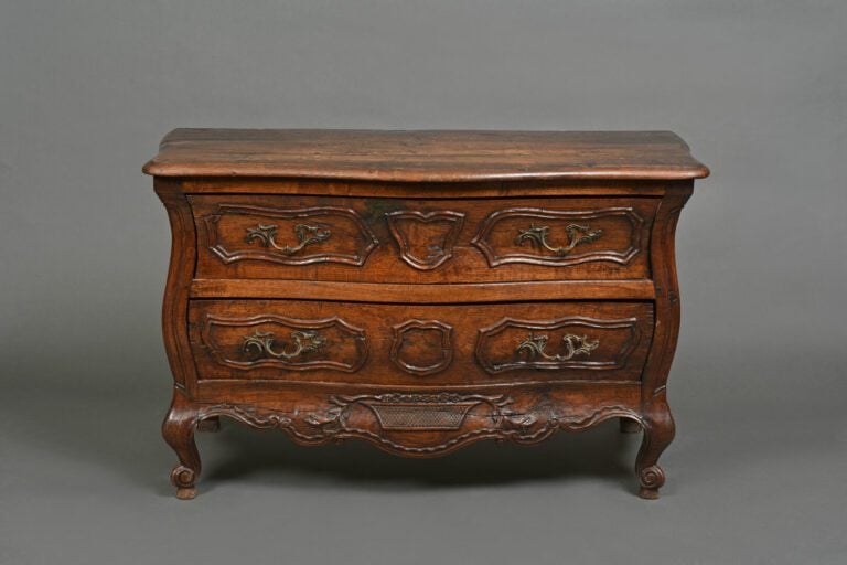 Commode à façade galbée en bois naturel mouluré et sculpté ouvrant à deux tioir…