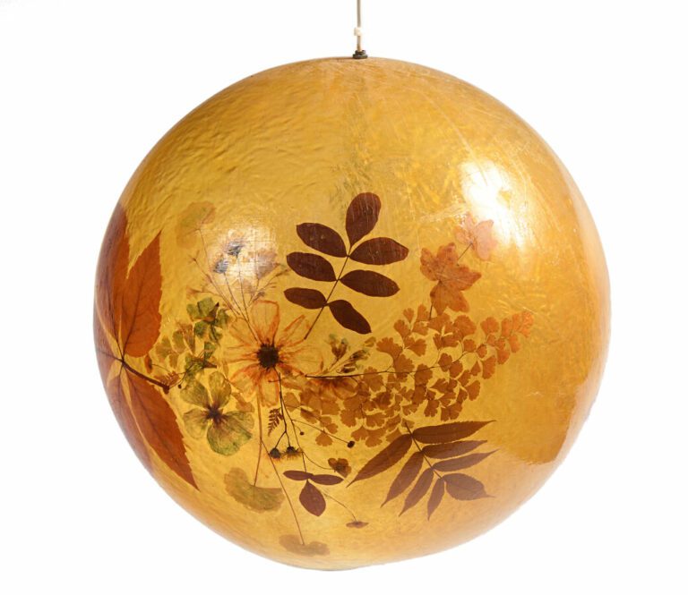 Trois suspensions boules en résine jaune à décor intercalaire de fleurs séchées…