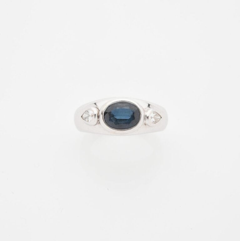 Bague jonc en or gris (750) ornée d'un saphir de taille ovale facettée, épaulé…